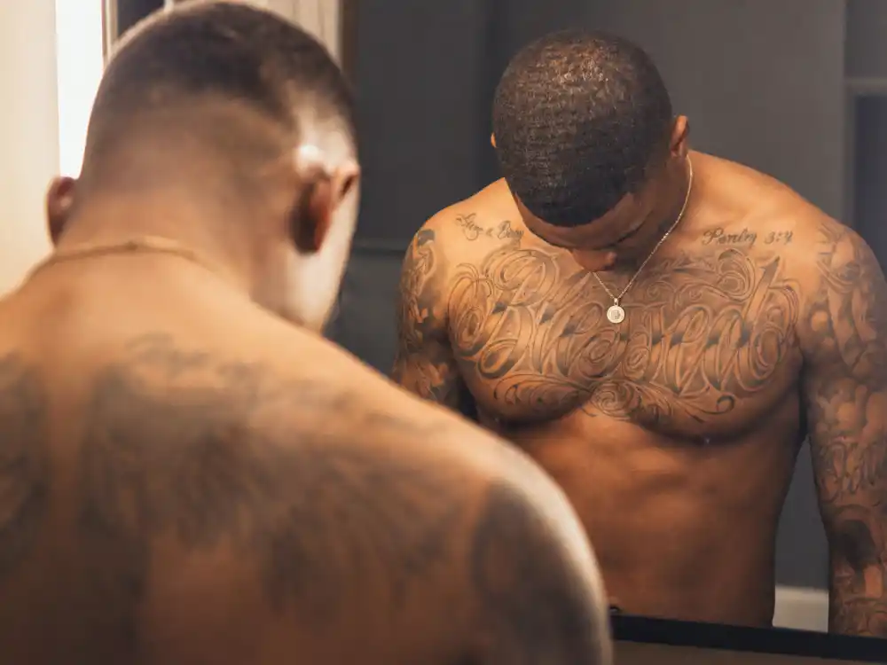 Chris Brown tattoos and their meanings — chest script tattoo and collarbone ink over-shoulder on athletic R&B artist