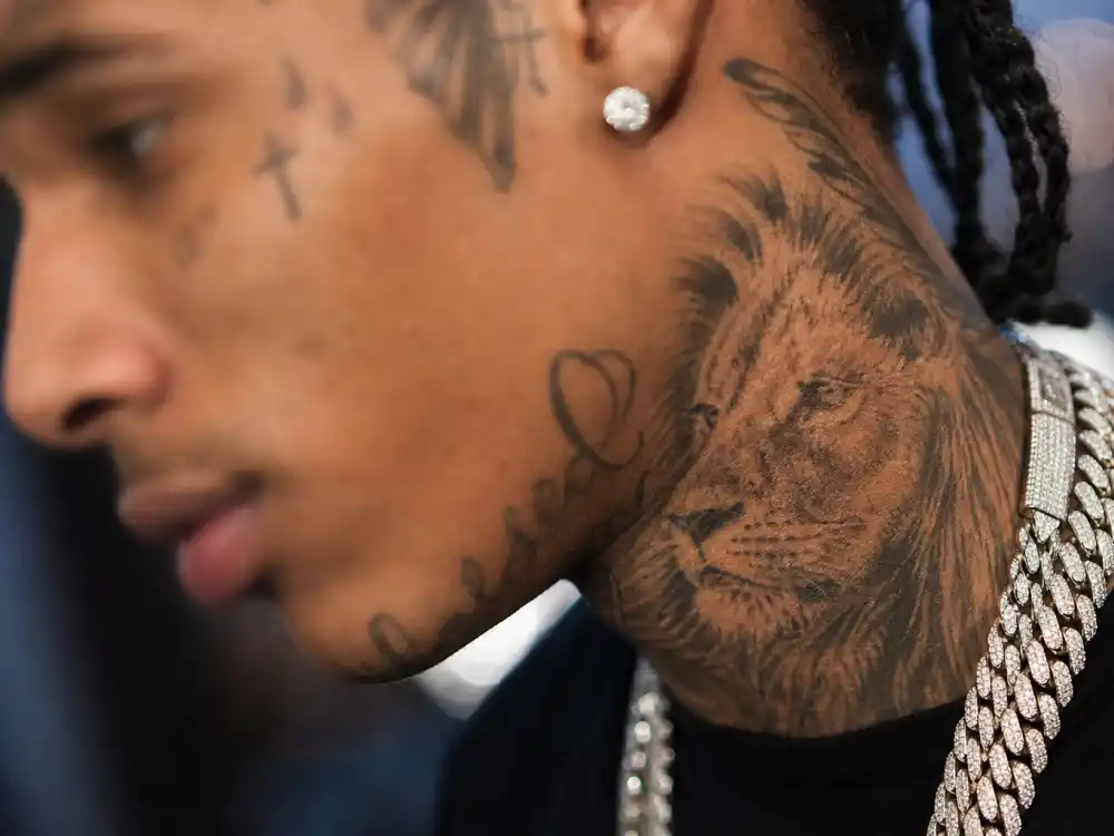 Chris Brown tattoos and their meanings — close-up of face and jawline tattoos with neck lion ink on R&B musician side profile