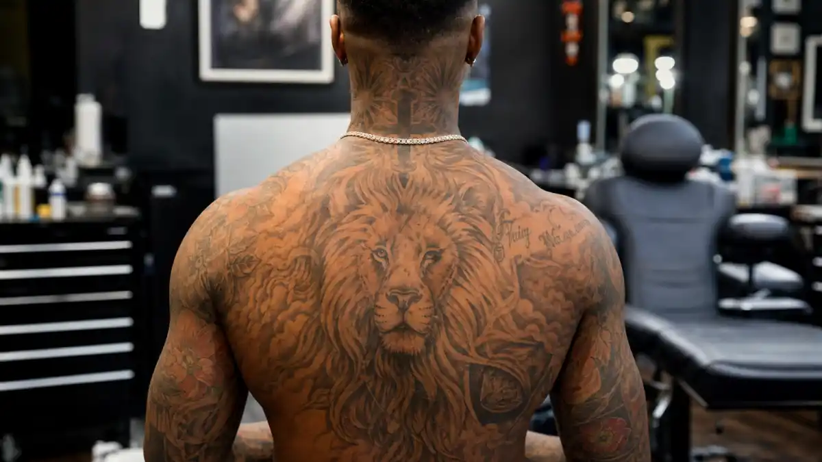 Chris Brown tattoos and their meanings — R&B singer seen from behind in tattoo studio with lion back piece and full arm sleeves visible