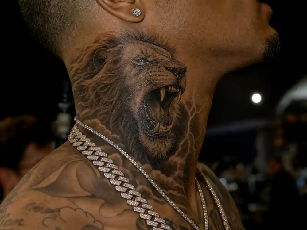Chris Brown tattoos and their meanings — detailed roaring lion neck tattoo close-up on R&B singer without identifiable face