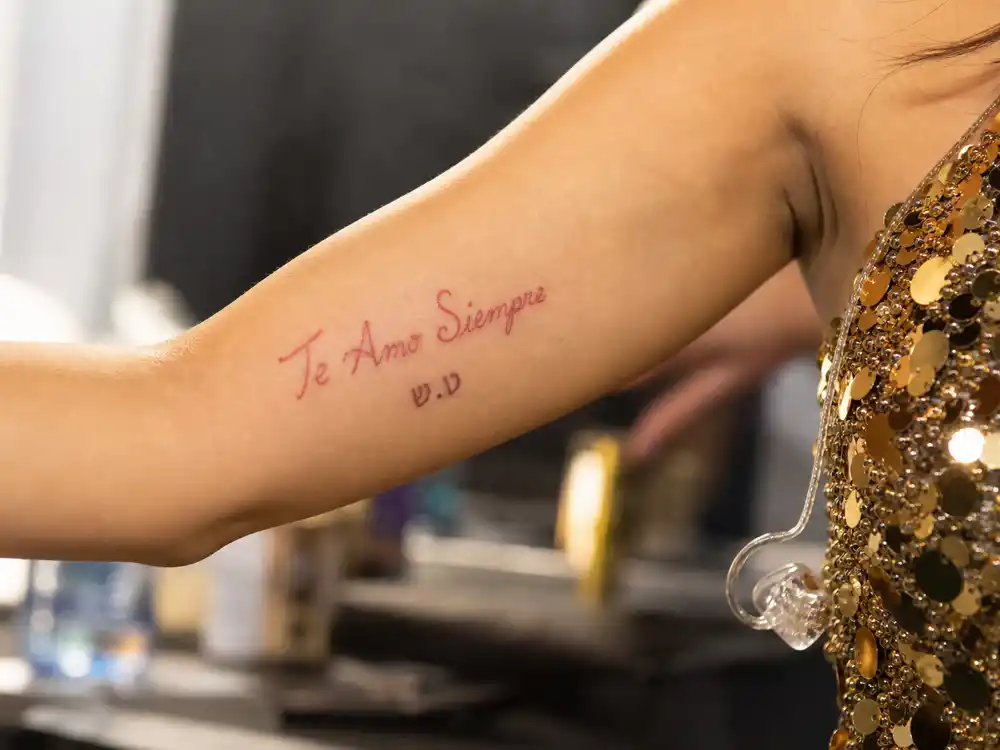Christina Aguilera tattoos and their meanings Te Amo Siempre elbow — red Spanish script with Hebrew Jordan Bratman initials on inner left elbow