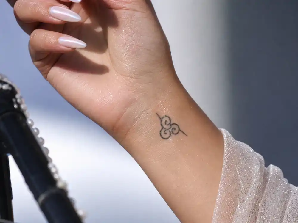 Christina Aguilera tattoos and their meanings wrist swirl — small abstract flower swirl tattoo on left wrist