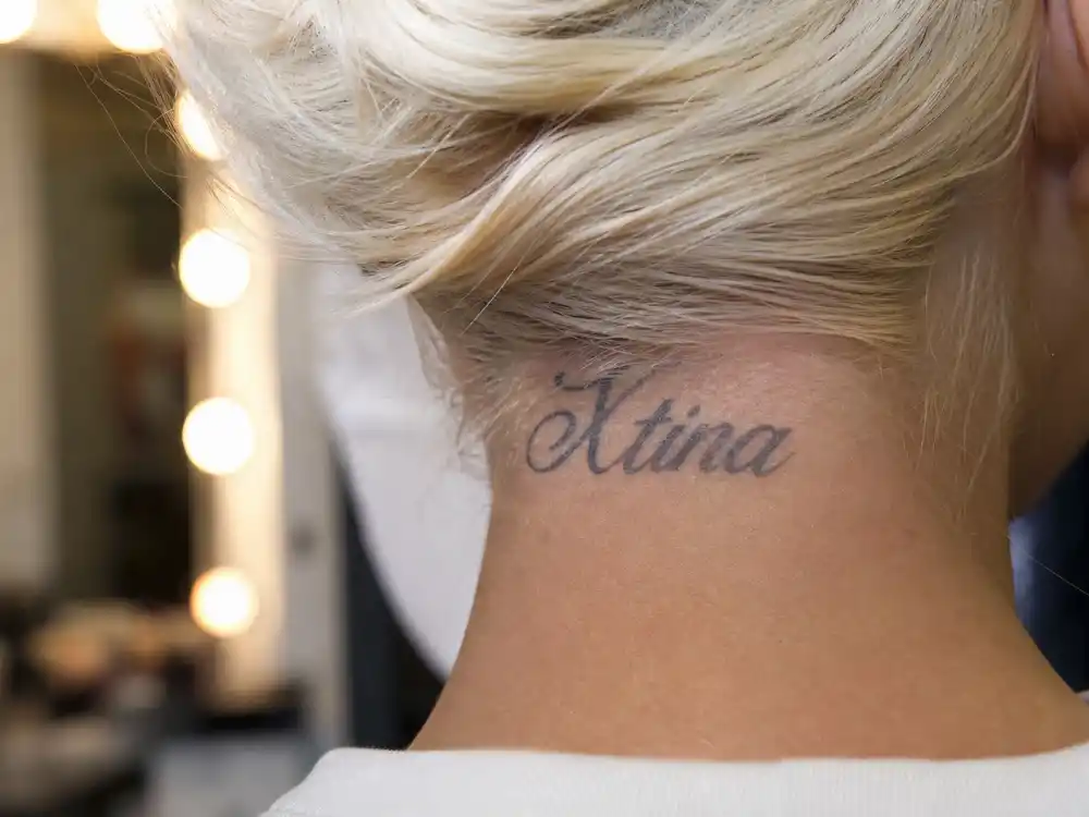 Christina Aguilera tattoos and their meanings Xtina neck — gray nickname script tattoo on back of nape