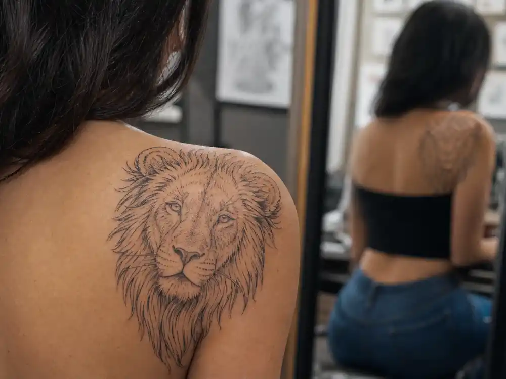 Christina Ricci tattoos and their meanings — Aslan lion outline tattoo from Chronicles of Narnia on right shoulder in studio close-up