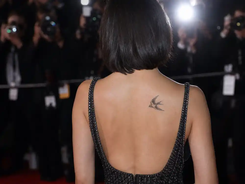 Christina Ricci tattoos and their meanings — small sparrow bird tattoo visible on upper back at red carpet from behind