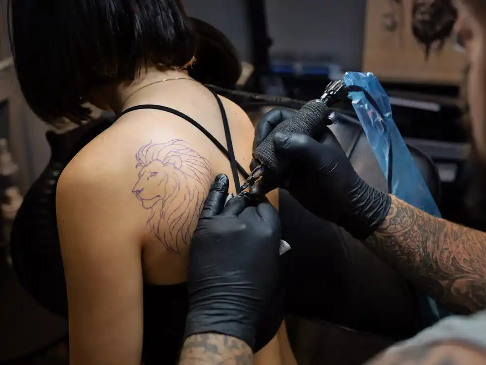 Christina Ricci tattoos and their meanings — tattoo artist inking Aslan lion shoulder tattoo during professional studio session