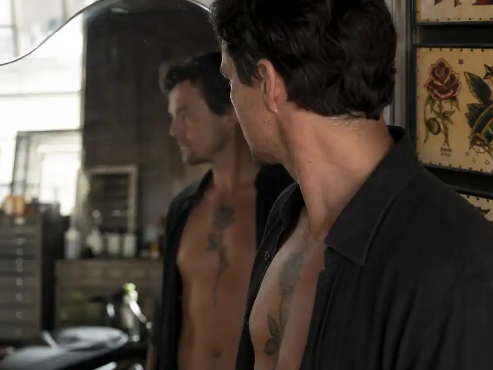 Colin Farrell tattoos and their meanings — chest rose tattoo visible over-shoulder in studio mirror reflection