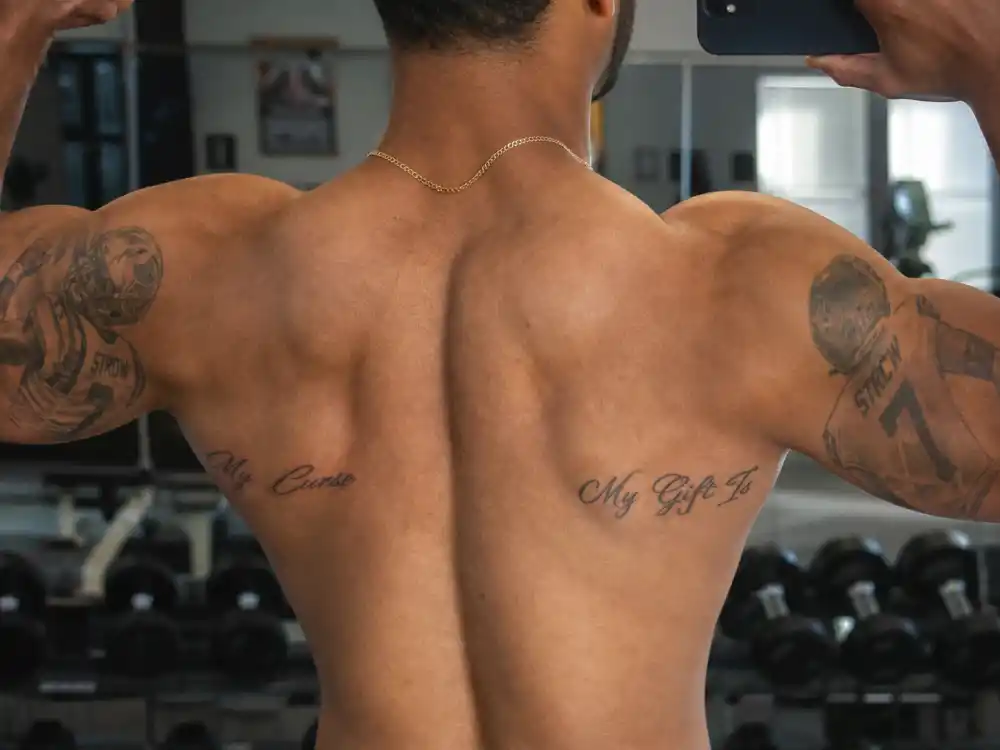Colin Kaepernick tattoos and their meanings — My Gift Is and My Curse inner bicep script tattoos on both arms