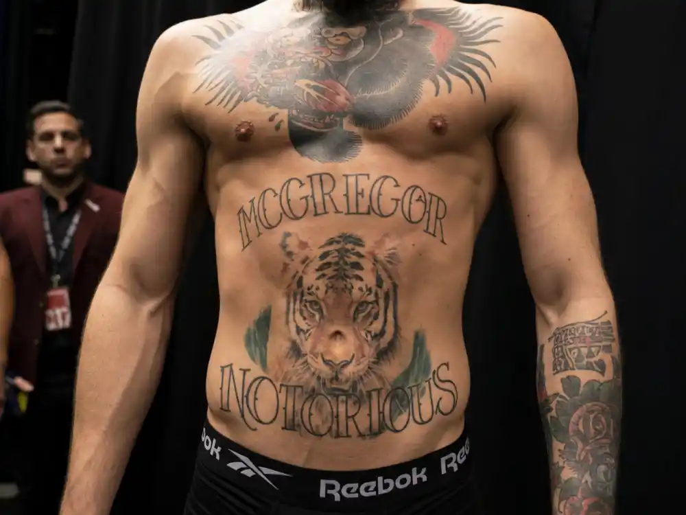 Conor McGregor tattoos and their meanings — MCGREGOR surname and NOTORIOUS nickname script tattoos on abdomen