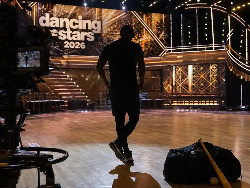 Dancing with the Stars 2026 cast guide athlete contestant — baseball player silhouette from behind practicing dance footwork on TV ballroom floor with camera dolly