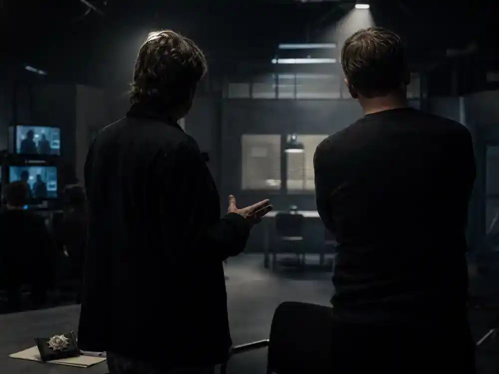 Dark Netflix cast and timeline explained Ulrich Nielsen — two adult actor silhouettes from behind rehearsing tense dialogue on dark German TV thriller soundstage