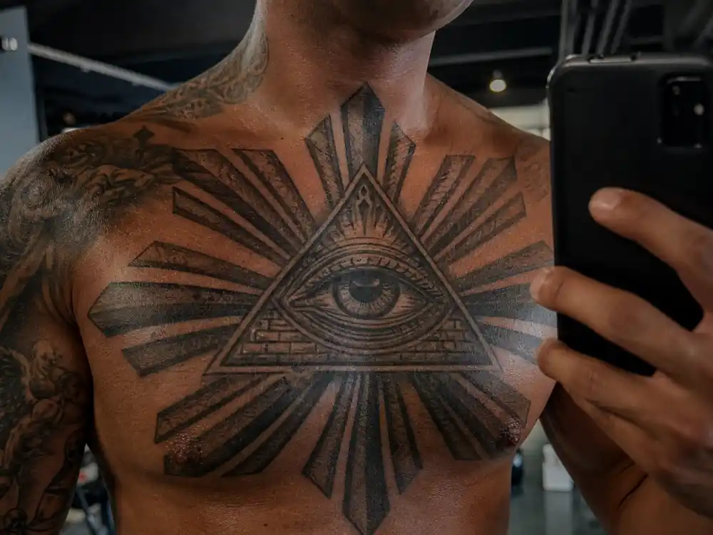 Dave Bautista tattoos and their meanings — Eye of Providence chest tattoo surrounded by Philippine sun rays in gym mirror