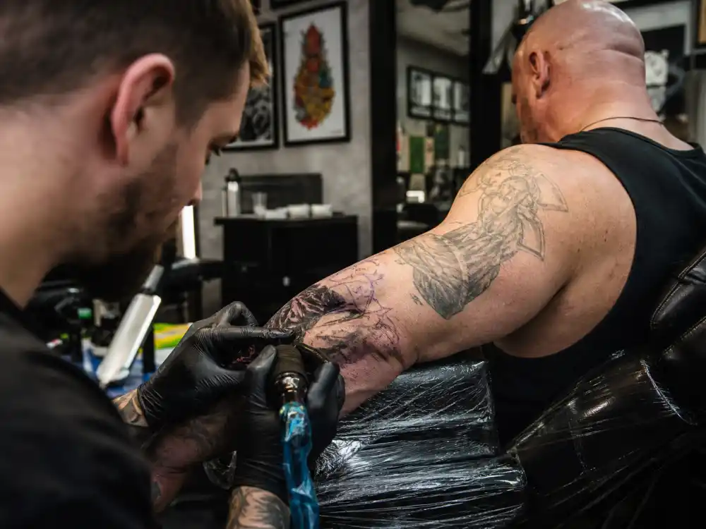 Dave Bautista tattoos and their meanings — tattoo artist cover-up session on forearm with fresh ink over faded design