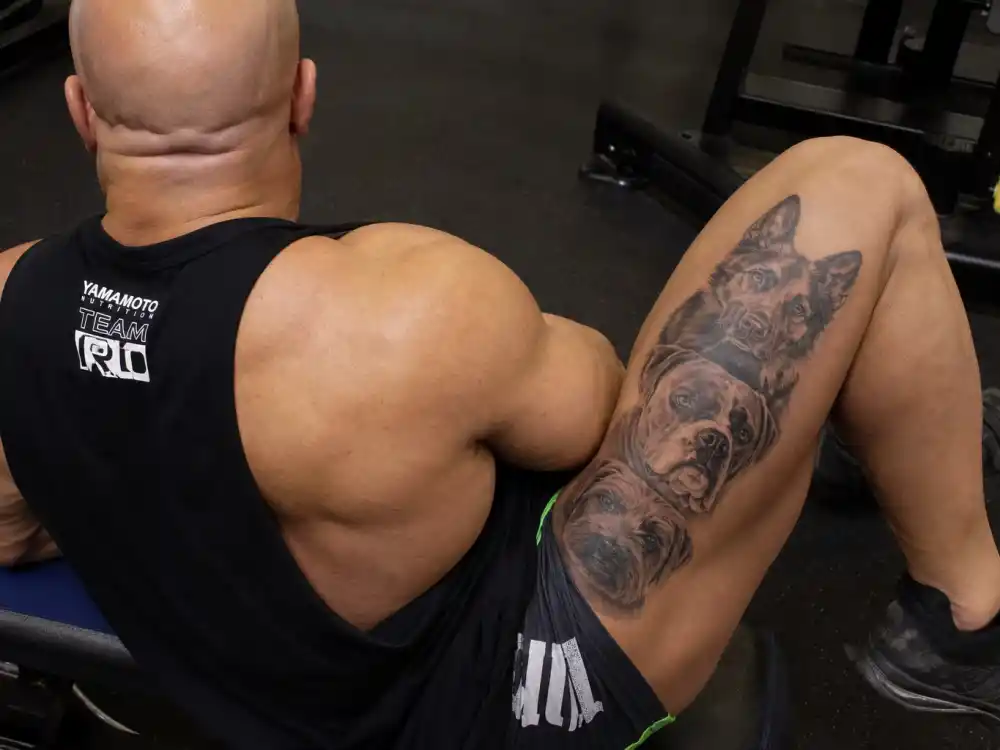 Dave Bautista tattoos and their meanings — three dog portrait tattoos on right thigh in black and grey realism style