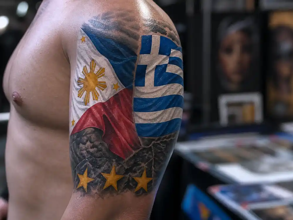 Dave Bautista tattoos and their meanings — Philippines and Greece flag tattoos on upper left arm with three stars on elbow