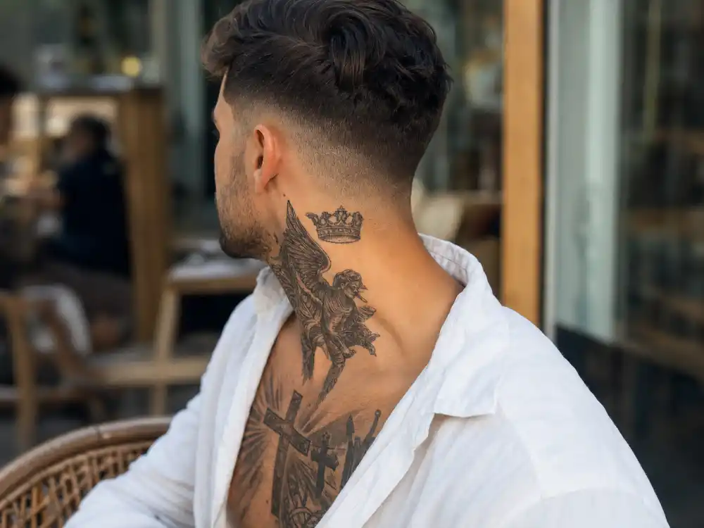 David Beckham tattoos and their meanings neck crown — crown neck tattoo and chest cross ink visible on athletic man in open collar shirt side-back angle