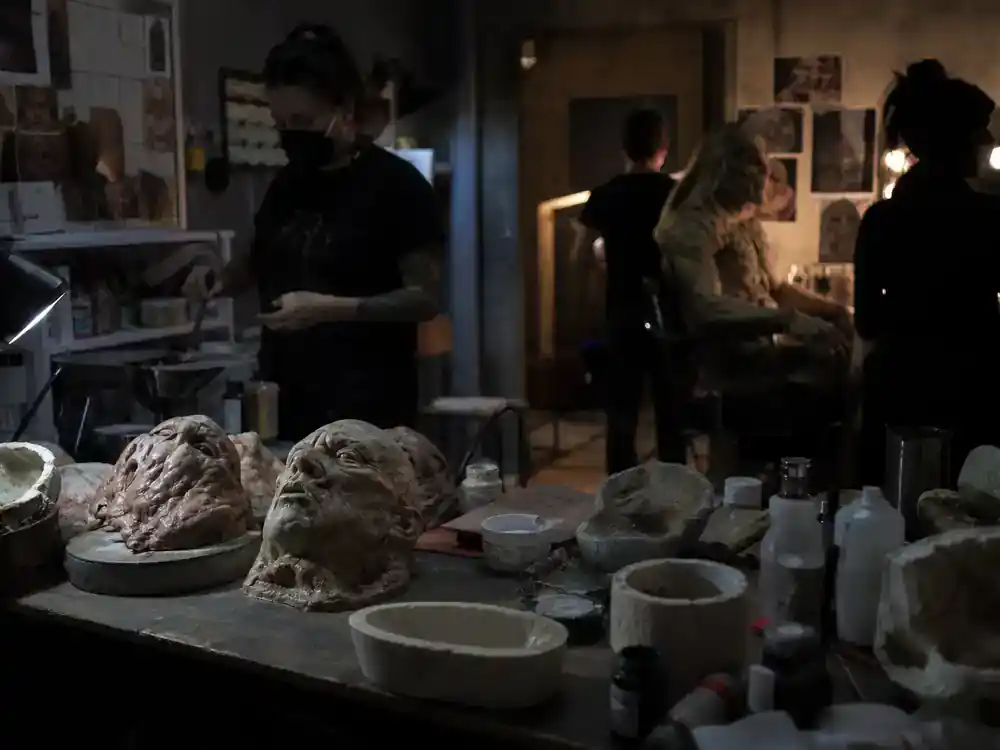 DC Universe 2026 movies and cast roadmap Clayface — horror film practical effects makeup station with prosthetics on table, crew silhouettes in dim light
