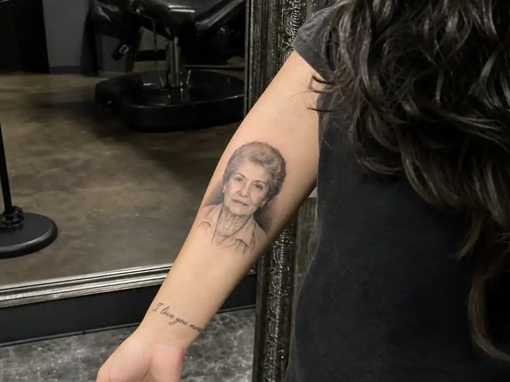 Demi Lovato tattoos and their meanings — great-grandmother portrait tattoo on forearm with I love you more wrist script in mothers handwriting below