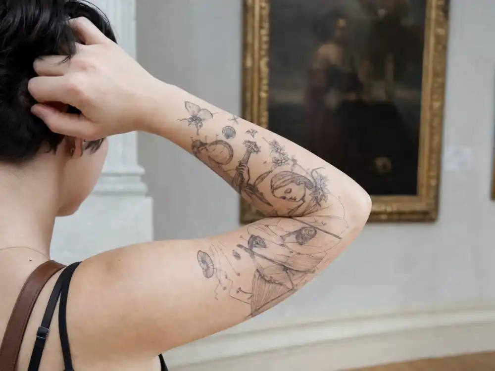 Doja Cat tattoos and their meanings — Fortunio Liceti-inspired art-history forearm tattoo in vintage natural-history engraving style over-shoulder angle