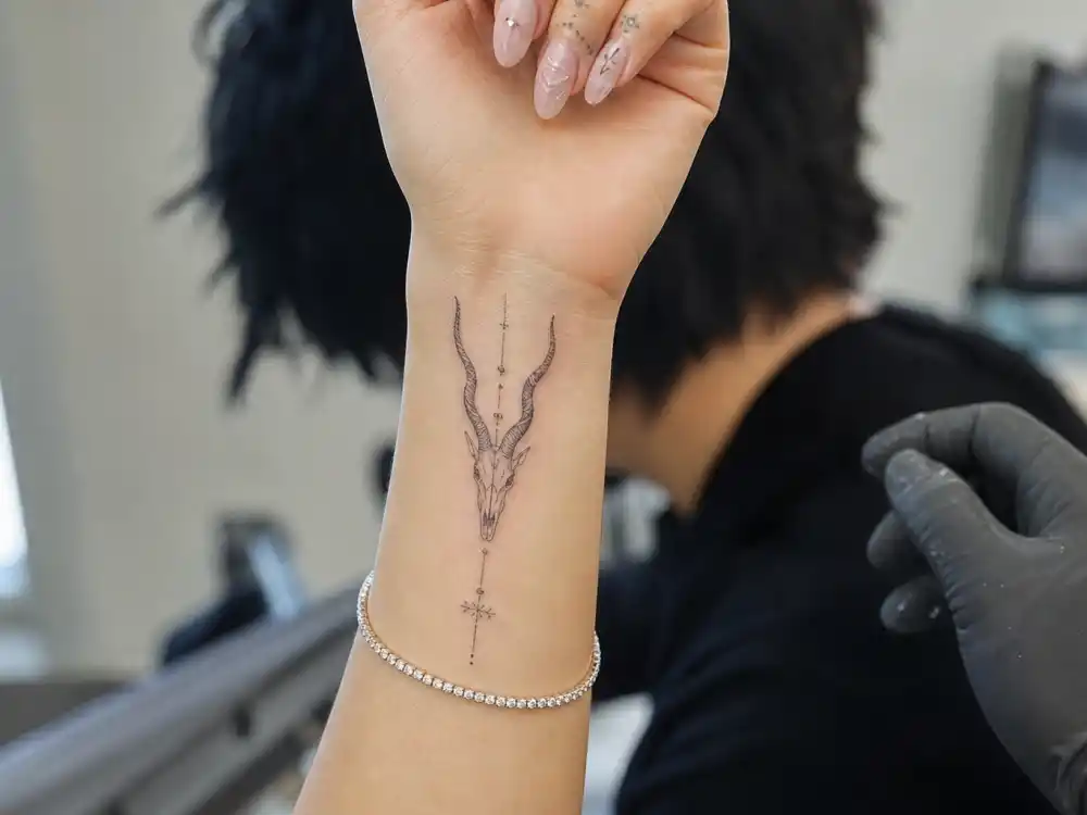 Doja Cat tattoos and their meanings — fine-line antelope skull wrist tattoo by Dr. Woo photographed during celebrity tattoo studio session