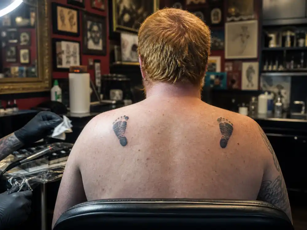 Ed Sheeran tattoos and their meanings back tattoo — daughters Lyra and Jupiter baby footprint ink on upper back in studio