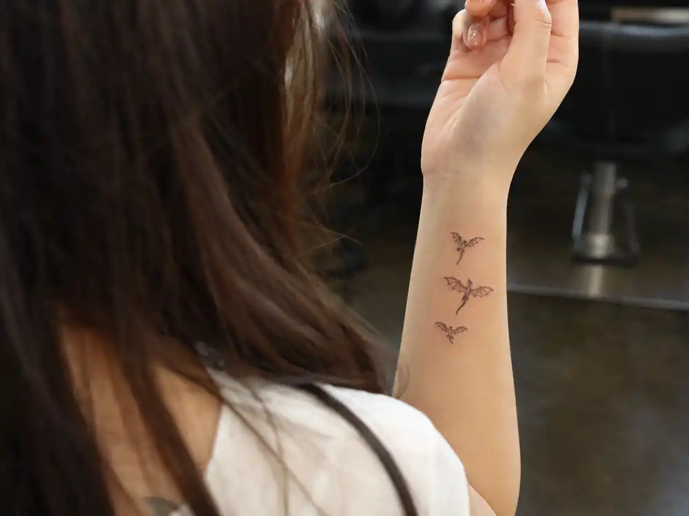 Emilia Clarke tattoos and their meanings dragons — three tiny flying dragon tattoos on right inner wrist Game of Thrones Mother of Dragons tribute