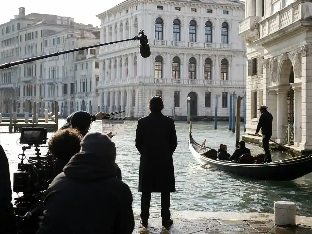 Emily in Paris season 5 cast and locations guide Venice — TV production crew filming on canal with gondola historic stone architecture and camera boom