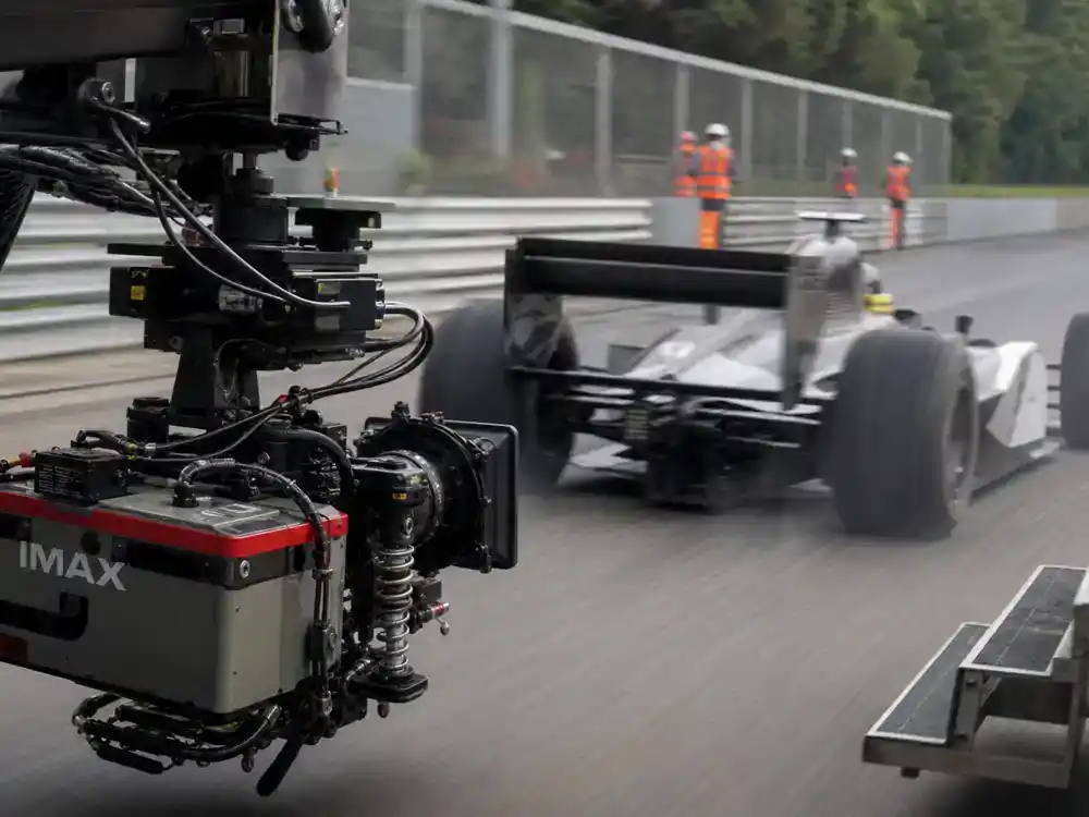 F1 movie Brad Pitt cast and racing facts on-track action — IMAX camera rig filming generic open-wheel race car during motorsport movie production