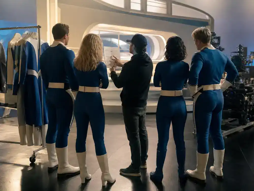 Fantastic Four First Steps cast and plot guide core four — ensemble cast silhouettes from behind on retro-futuristic soundstage in blue hero costumes