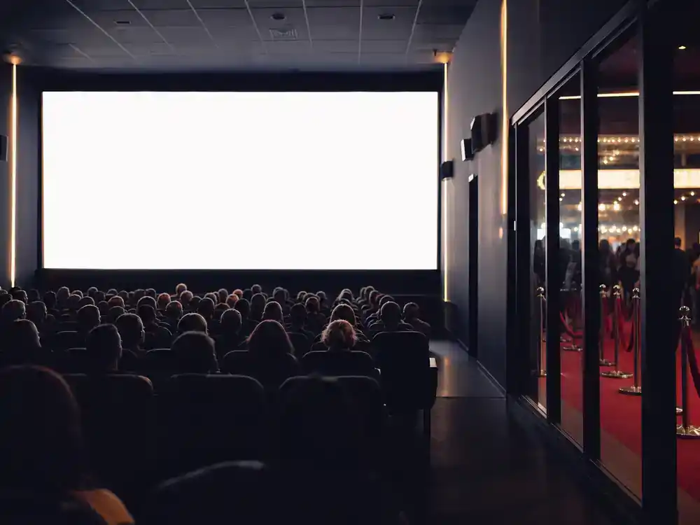 Fast and Furious cast net worth 2026 ranked box office — packed cinema auditorium silhouettes during blockbuster premiere night with red carpet lobby visible