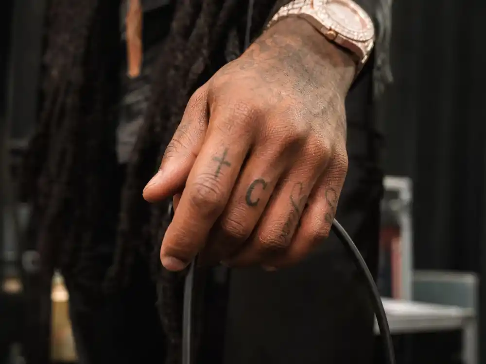 Future tattoos and their meanings — tattooed hand with letter C on ring finger and finger script ink backstage