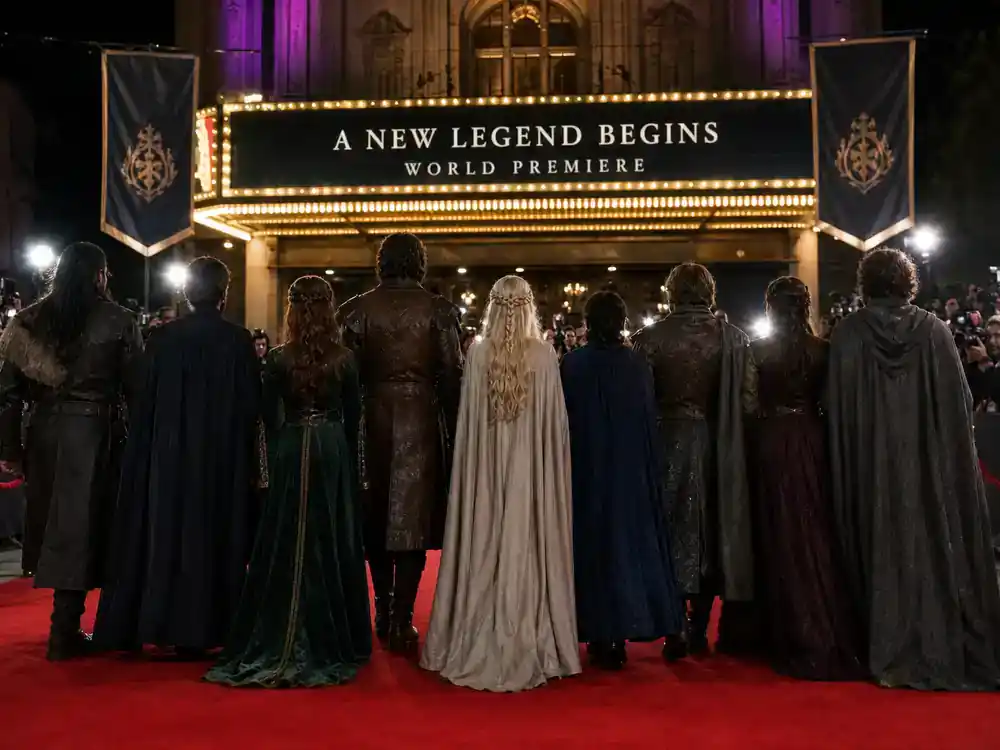 Game of Thrones cast net worth 2026 ranked ensemble — fantasy TV drama cast silhouettes from behind walking red carpet toward theater marquee at premiere night