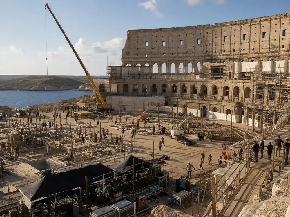 Gladiator 2 behind the scenes cast facts Malta Colosseum filming — massive amphitheater replica under construction with crane and Mediterranean coastline