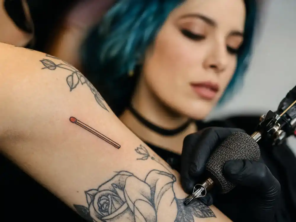 Halsey tattoos and their meanings — close-up of old-school matchstick tattoo on forearm from fan matching session