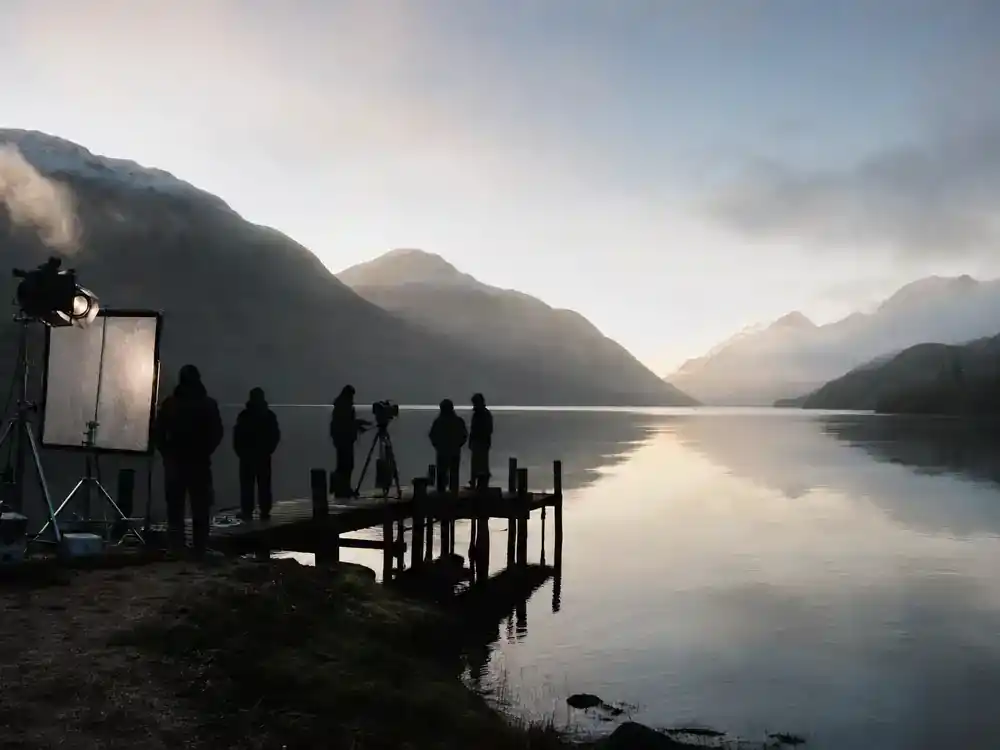 Harry Potter filming locations in Scotland guide Loch Shiel — camera crew on pier at calm Scottish loch with mountain reflections film production setup