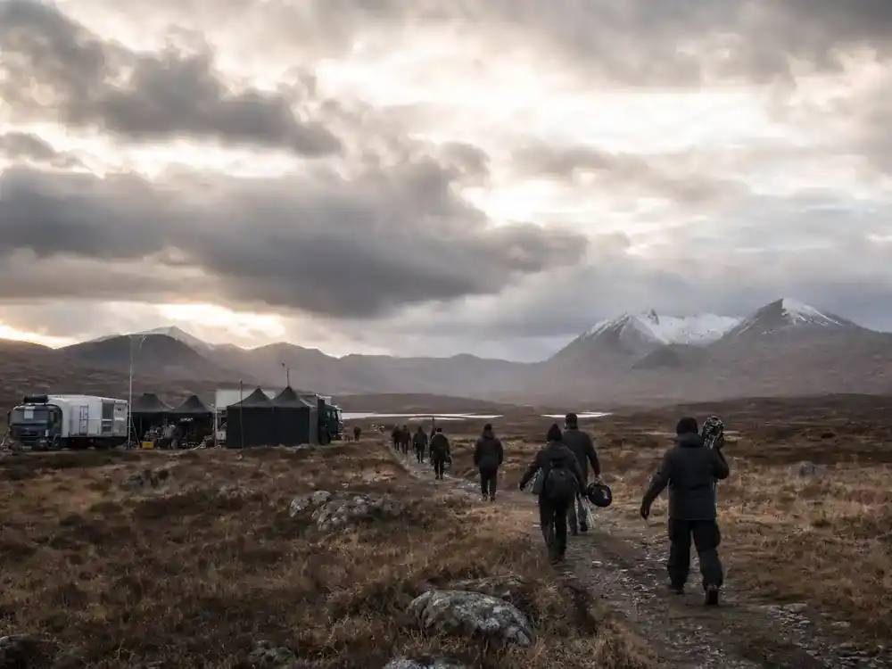 Harry Potter filming locations in Scotland guide Rannoch Moor — wide wilderness moor with film base camp trucks and crew silhouettes toward distant peaks