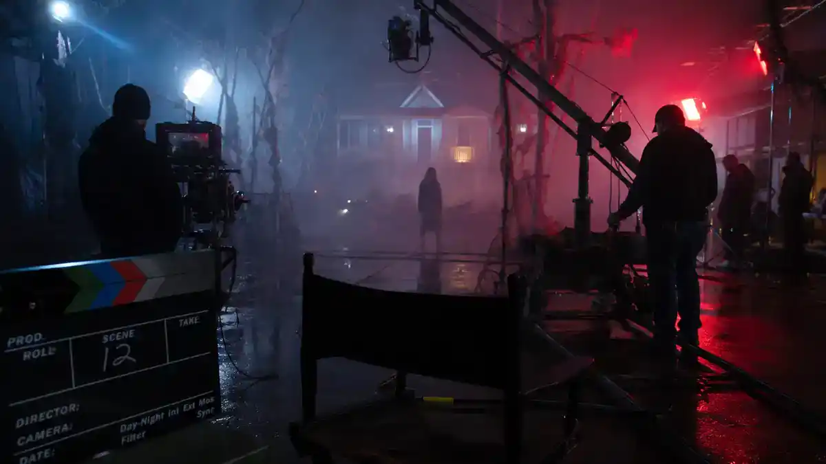 Horror franchise sequels 2026 cast guide — foggy horror film soundstage with clapperboard director chair and crew silhouettes during sequel production