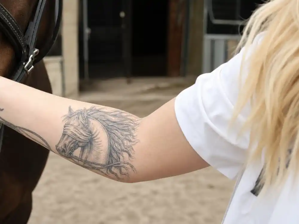 Iggy Azalea tattoos and their meanings blindfolded horse — etching-style forearm tattoo honoring equestrian therapy passion at stable