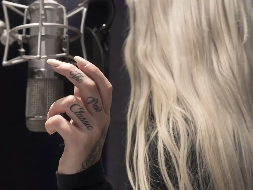 Iggy Azalea tattoos and their meanings The New Classic — right hand finger script tattoos spelling debut album title in cursive at recording studio