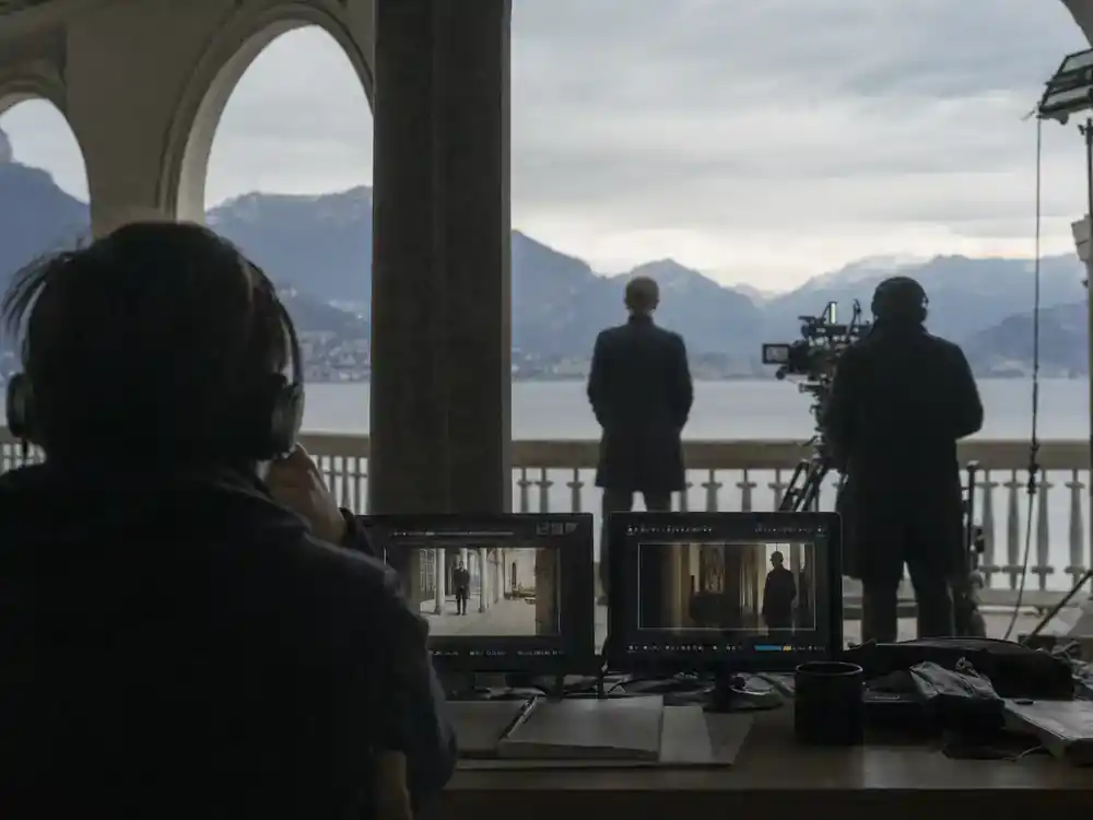 James Bond next movie cast rumors explained Denis Villeneuve director — director silhouette reviewing monitors on spy thriller film set, face turned away