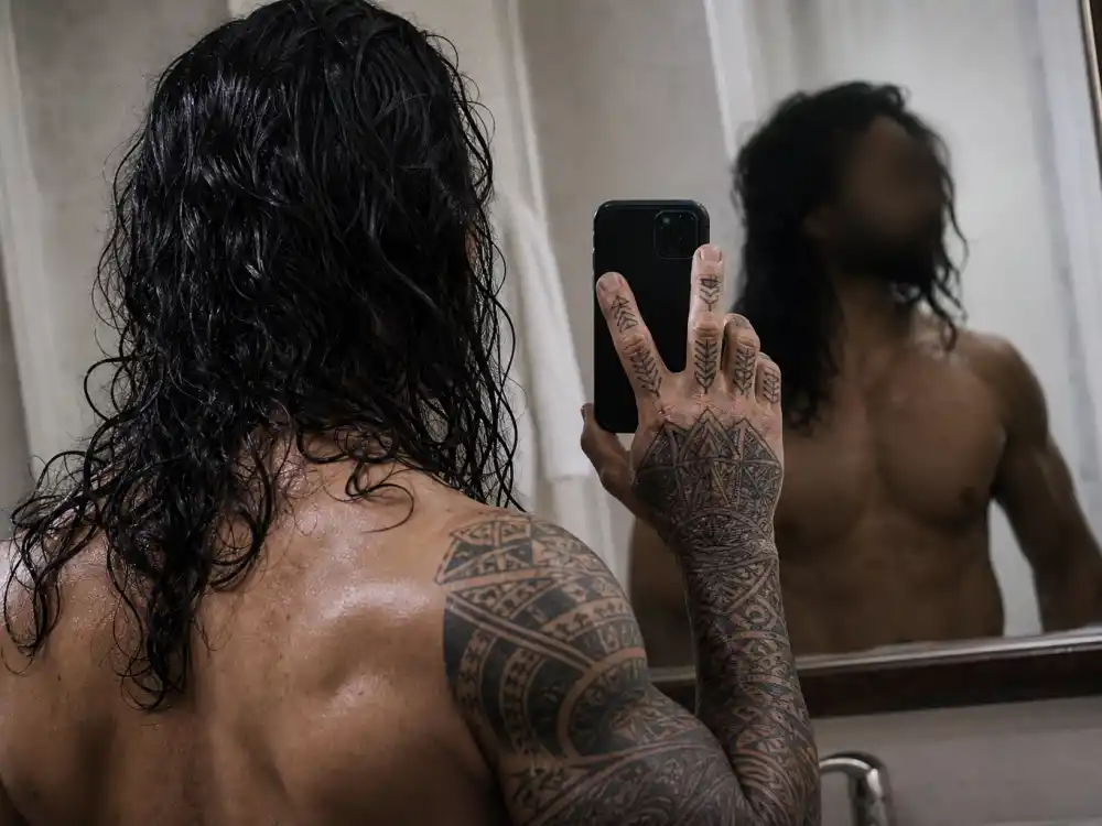 Jason Momoa tattoos and their meanings hand ink — tribal finger and knuckle tattoos mirror angle from behind with face blurred