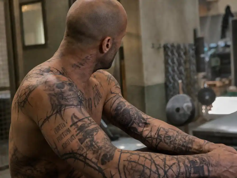 Jason Statham tattoos and their meanings — Death Race tribal prison character tattoos on forearms and chest close-up