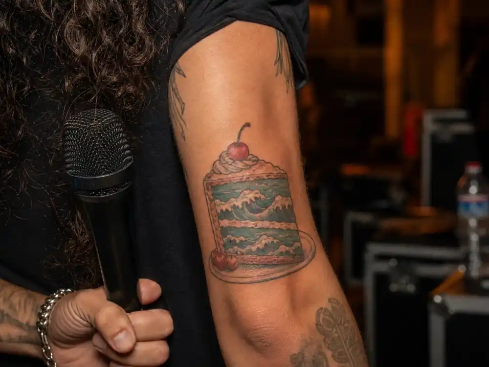 Joe Jonas tattoos and their meanings cake by ocean — slice of cake with wave tattoo on forearm linked to DNCE hit song