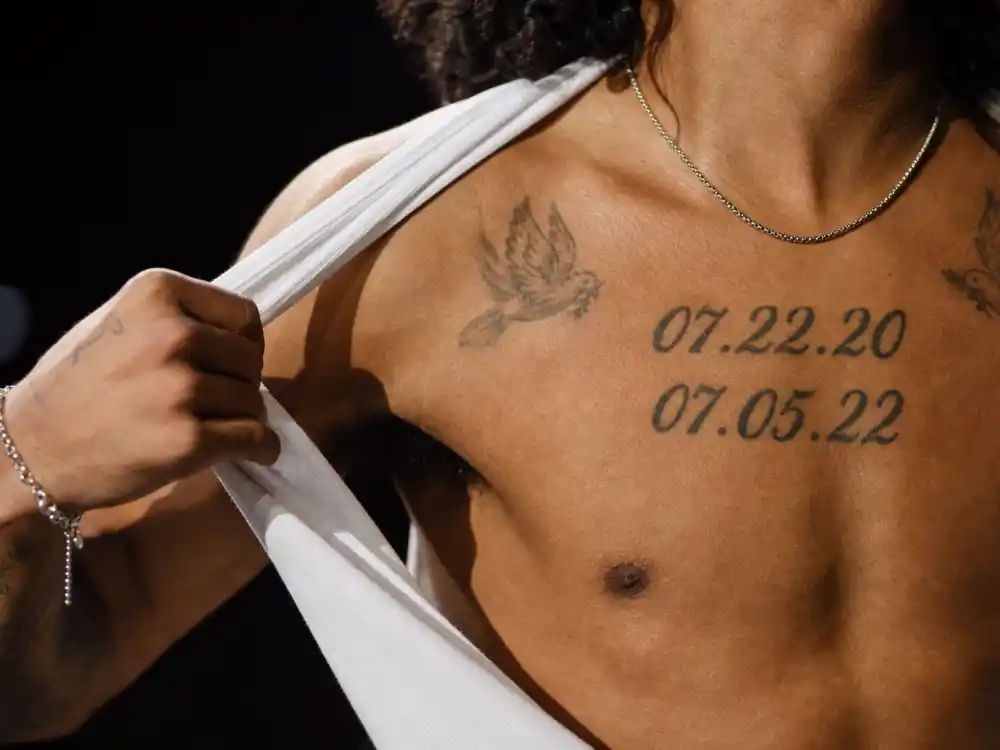 Joe Jonas tattoos and their meanings chest dates — daughters birth dates 07.22.20 and 07.05.22 tattooed on concert stage torso