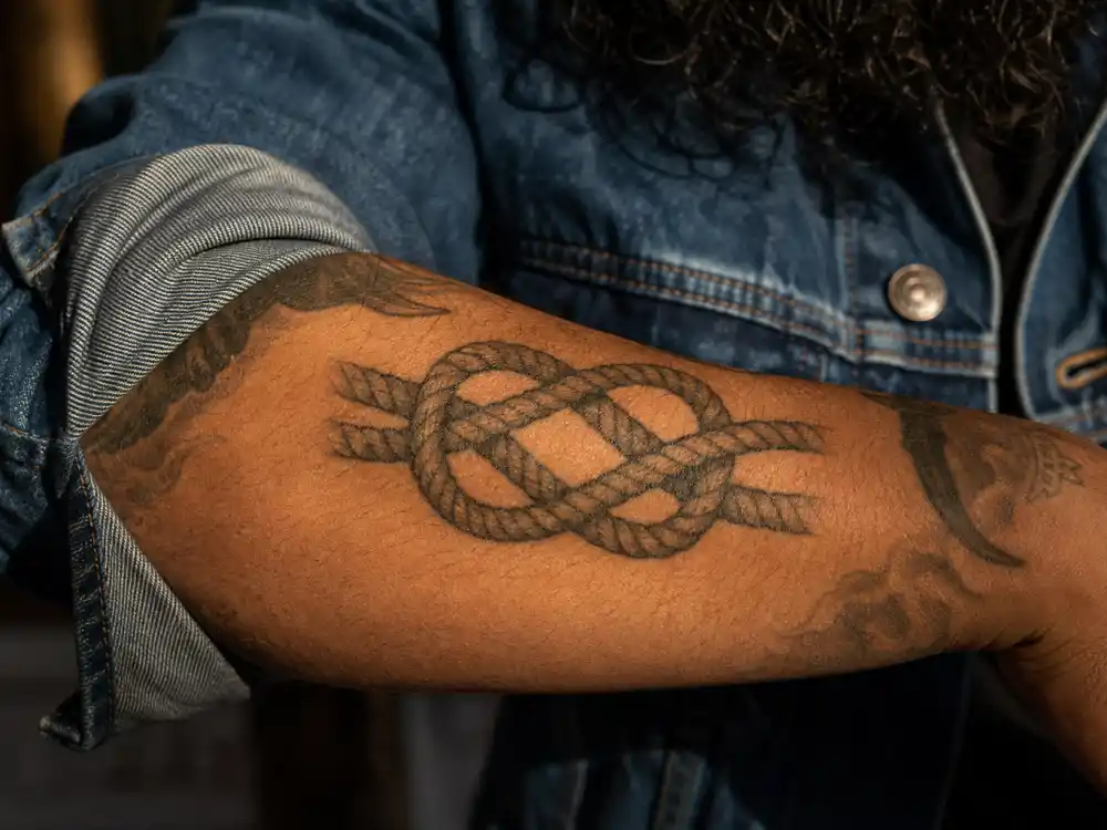 Joe Jonas tattoos and their meanings rope family — interwoven rope knot forearm tattoo tribute to parents and four Jonas brothers