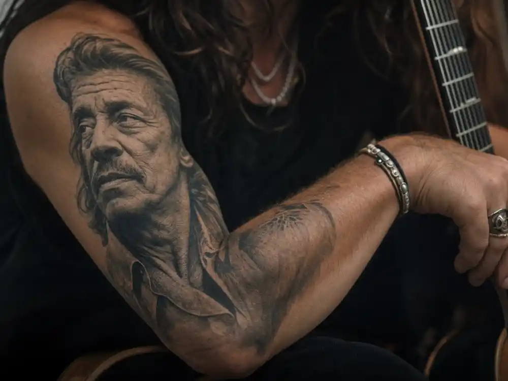 Johnny Depp tattoos and their meanings — black-and-grey grandfather portrait tattoo on forearm sleeve close-up