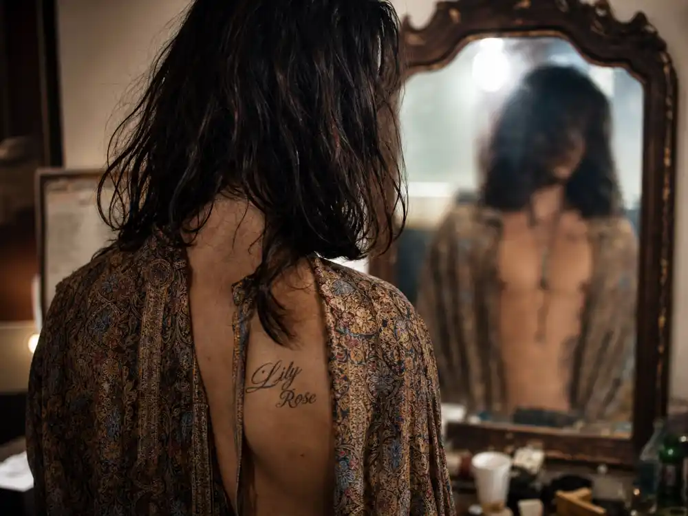 Johnny Depp tattoos and their meanings — Lily Rose chest tattoo dedication to daughter seen from behind in dressing room mirror