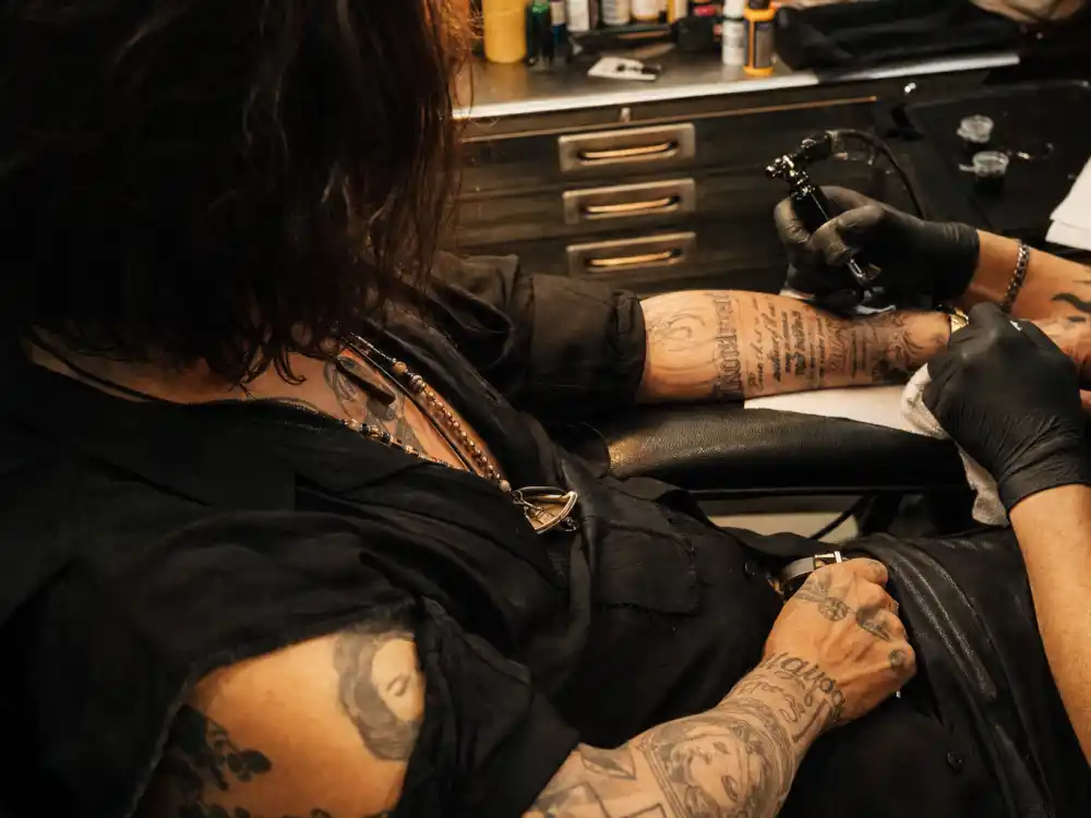 Johnny Depp tattoos and their meanings — tattoo studio session with artist working on portrait sleeve forearm ink