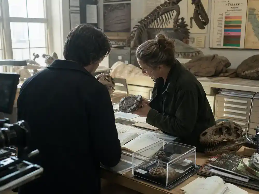 Jurassic World Rebirth cast and characters guide Dr. Henry Loomis — museum paleontology department with fossil casts and research notebooks during film consultation