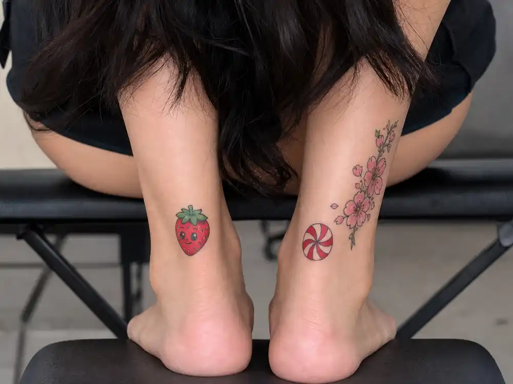 Katy Perry tattoos and their meanings — cartoon strawberry peppermint and cherry blossom ankle tattoos photographed from above